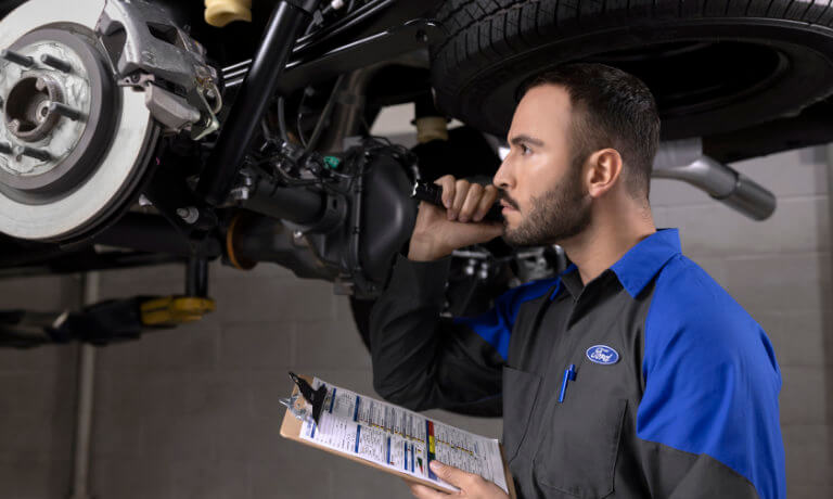 Ford Service Technician examining under car